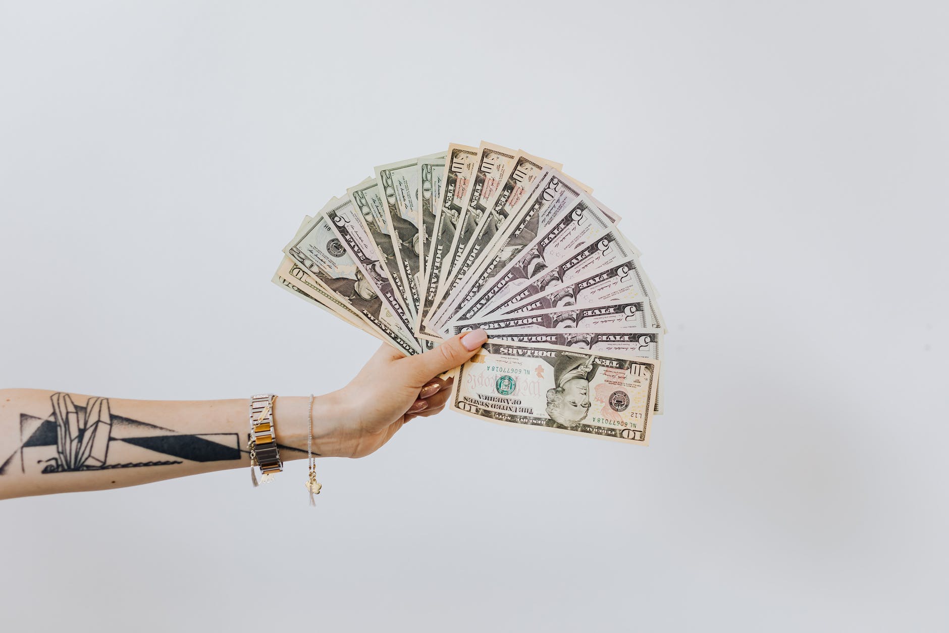 hand holding fan of us dollar bills