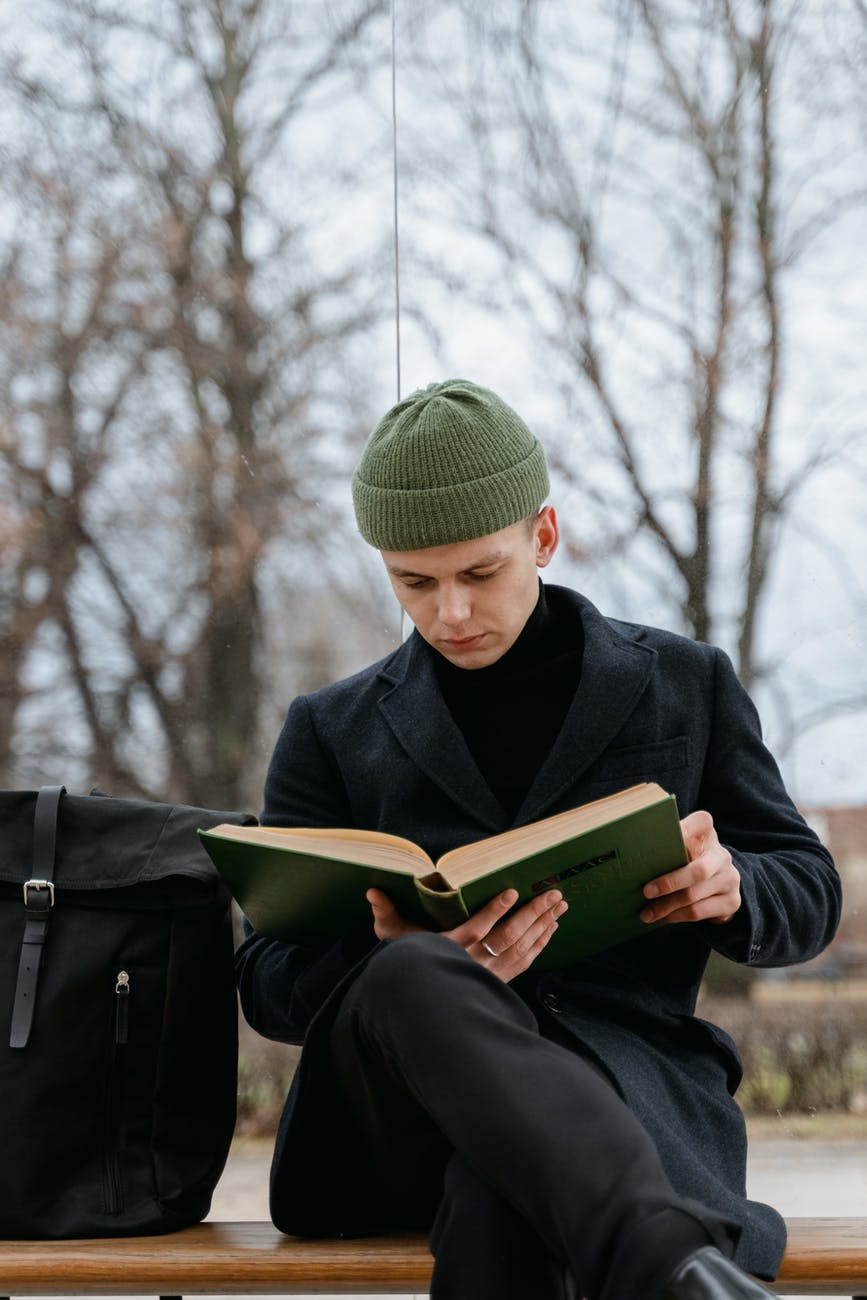 a man wearing a green bonnet reading a book